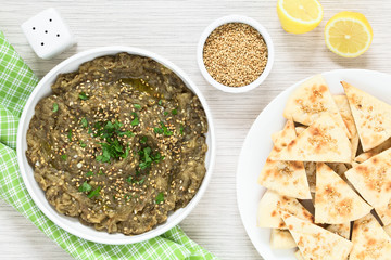 Homemade roasted eggplant dip or spread (baba ganoush in the Mediterranean cuisine), olive oil, sesame, parsley on top, homemade sesame pita chips on the side