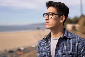 Young Asian man looking far away thinking