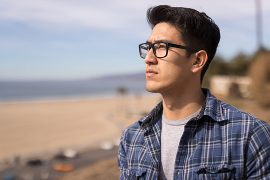 Young Asian man looking far away thinking