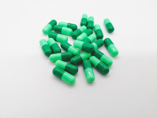 Medication and healthcare concept. Many green capsules of Cephalexin 500 mg. isolated on white background, used to treat serious infections caused by bacteria. Selective focus and copy space.