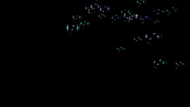 Colorful soap bubbles in slow motion on a black background