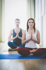 Fototapeta premium Young healthy couple in yoga position on white background