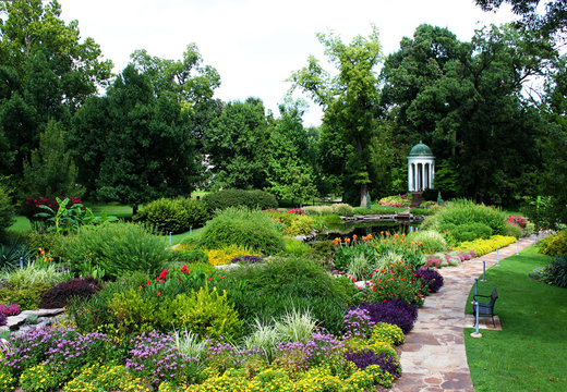 Formal gardens pond and pavillion in springtime with lush flowers and green trees
