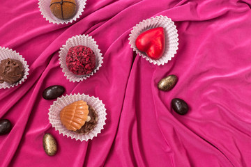 handmade chocolates, Opera glasses and a pink cloth on white background