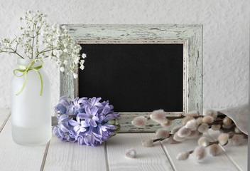 Spring flowers around a blackboard in rustic frame, text space