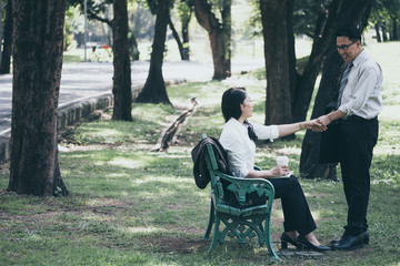 Happy Asian business man and woman talking in the public park after finish work.