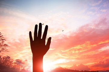 Belief, praise and worship concept: Silhouette christian people hand rising over blurred cross on spiritual light background