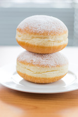 Two traditional Polish donuts (Paczek) with powdered sugar on white plate