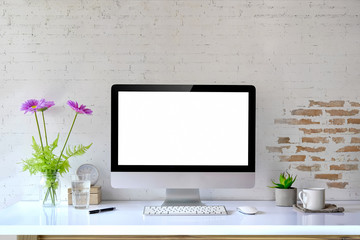 Mockup desktop Blank screen modern computer, coffee mug, house plant, bouquet and office supplies.