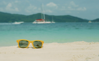 Fototapeta na wymiar Bright orange Fashion sunglasses on the white sand of a tropical beach. Vintage look. Travel and vacation concept. with copy space