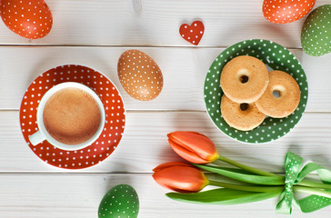 Obraz na płótnie Canvas Top view on espresso cup, plate of cookies, Easter eggs and tulips on light wood