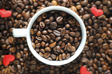 White cup with coffee beans on the coffee beans background.