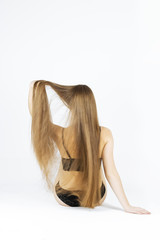 fashion studio photo of beautiful young woman showher luxurious long hair, natural color, back view, arms
