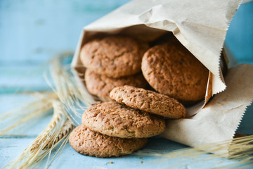 fresh oatmeal cookies in a bag made of paper on wooden background
