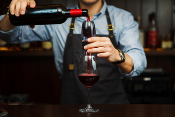 Male sommelier pouring red wine through aerator into glass.