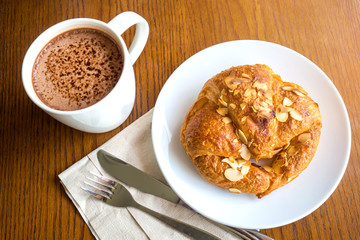 Happy breakfast with Delicious almond croissant and a cup of hot chocolate.