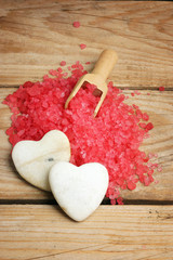 White stones in the form of hearts on a hill of red salt for a bath, romance in a spa salon