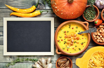 Blank blackboard next to a bowl of pumpkin soup and ingredients