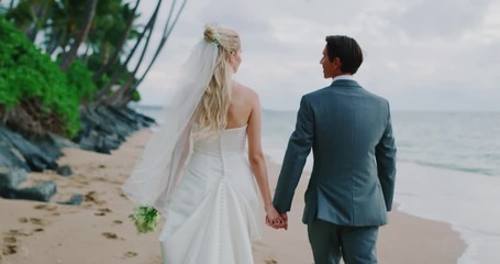 Bride and groom walking down the beach at sunset