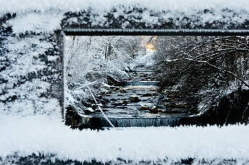 mountain stream framed by frozen fence