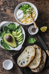 Ingredients for cooking avocado, spinach, egg salad on toast sandwich. Healthy food breakfast, snack on wooden background, top view. Flat lay