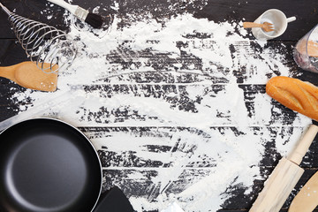 Kitchen utensils with wooden spoon on black wood table and flour background with copy space.