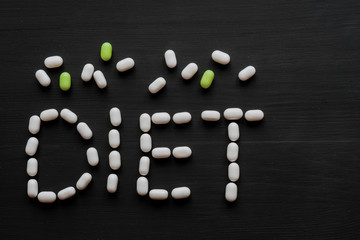 Fototapeta na wymiar Medical concept written with pills word DIET On black wooden background with copy space