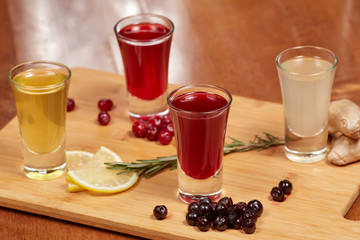 Flavored fruit liqueurs on wooden board. Citrus, berries, ginger