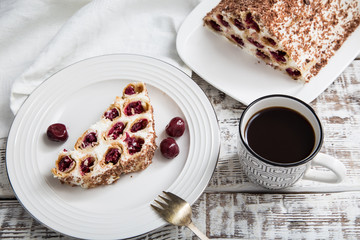 cake with cherries, cream and chocolate on a light wooden background