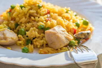 paella with chicken and seafood on white plate. Spanish dish served on table