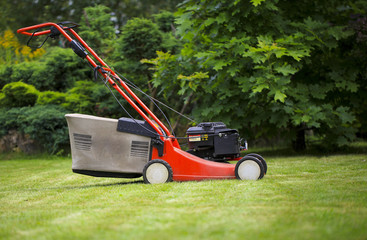 Blurred background of the home garden and lawn mower on mown grass.