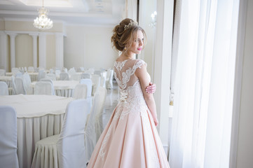 A beautiful woman in a pink wedding dress in a big festive hall