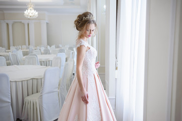 A beautiful woman in a pink wedding dress in a big festive hall