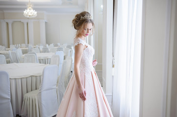 Fototapeta premium A beautiful woman in a pink wedding dress in a big festive hall