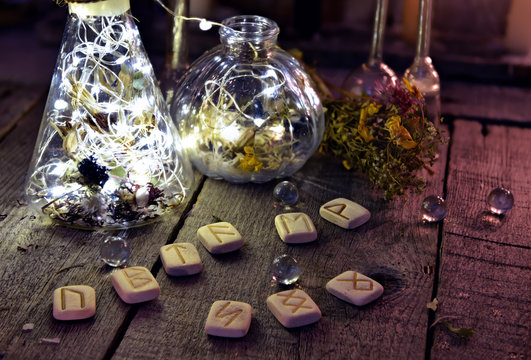 Ancient runes with magic bottles and crystals on witch table. Occult, esoteric, divination and wicca concept. Halloween background with vintage objects