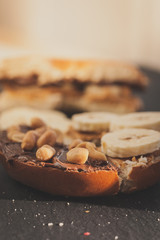 Tasty breakfast: Bagel with peanut butter, banana slices, chocolate ant salty peanuts
