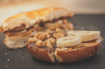 Tasty breakfast: Bagel with peanut butter, banana slices, chocolate ant salty peanuts