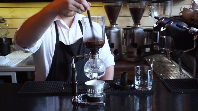 Barista stirring Syphon coffee maker in coffee shop