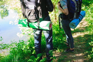 Young couple hikers in forest. sports man and woman with backpacks on road in nature