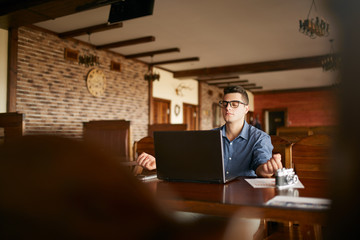 Businessman meditates sitting at table and laptop in office. Company leader practicing yoga during...