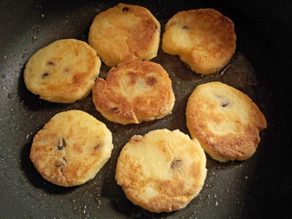 Freshly baked cottage cheese pancakes with raisins. Frying process. Top view