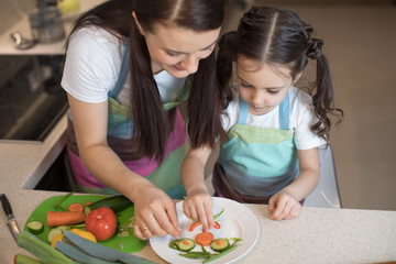 Obraz na płótnie Canvas Pretty mother and her kid making vegetable salad