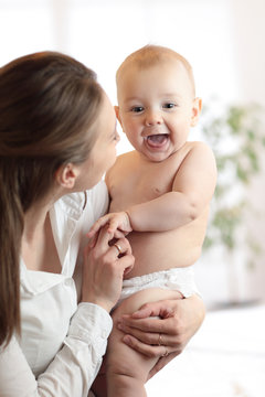 Happy family laughing faces, mother holding cute child baby boy. Young woman and her small son have a fun pastime.