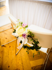 The bride's chair is decorated with flowers with roses in white