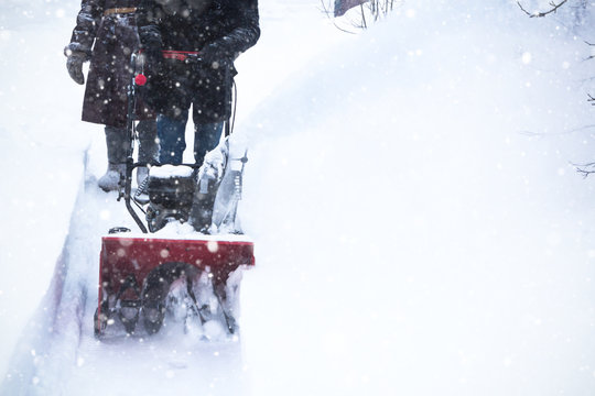 Man clears snow with snow blower, winter snowfall