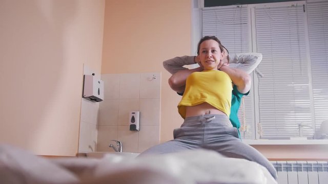 Manual therapist massaging and examining a young woman stretching her spine