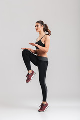 Full-length image of strong-willed female fitness trainer of instructor in sportswear warming up...