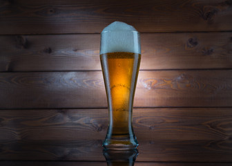 Glass of golden beer on wood background