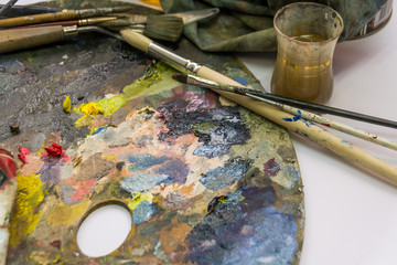 set of different brushes and oil paints to paint scattered on a dark wooden table top view
