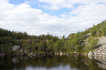 Fototapeta premium View of small lake in the valley, beautiful landscape of norwegian nature, sunny day, hiking way to Preikestolen cliff (Prekestolen or Pulpit Rock), famous popular travel landmark in Forsand, Norway